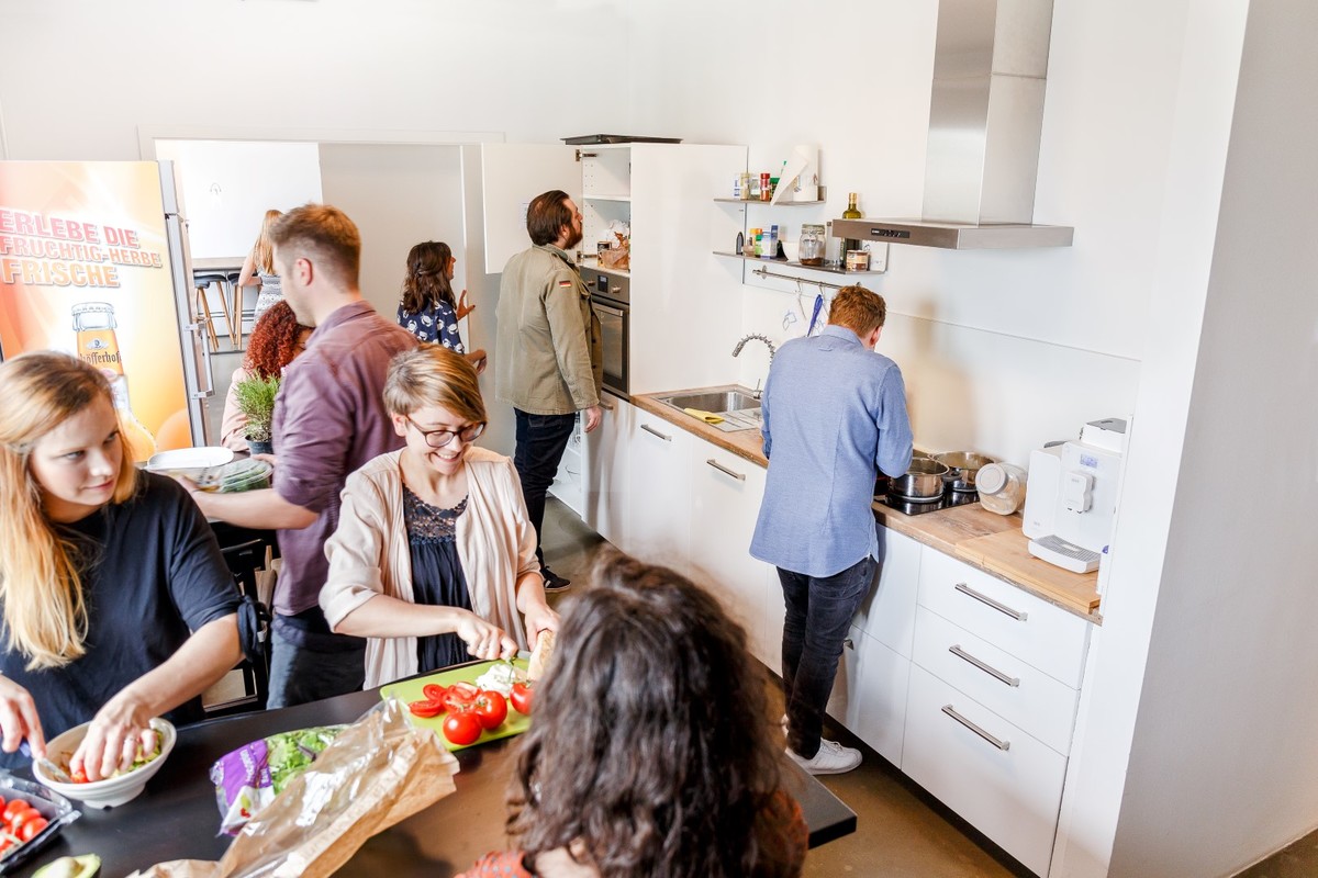 Mehrere Personen bereiten in einer hellen Küche gemeinsam Essen vor.